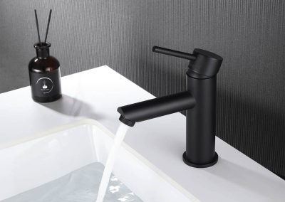 Black bathroom tap with water running into basin full of water